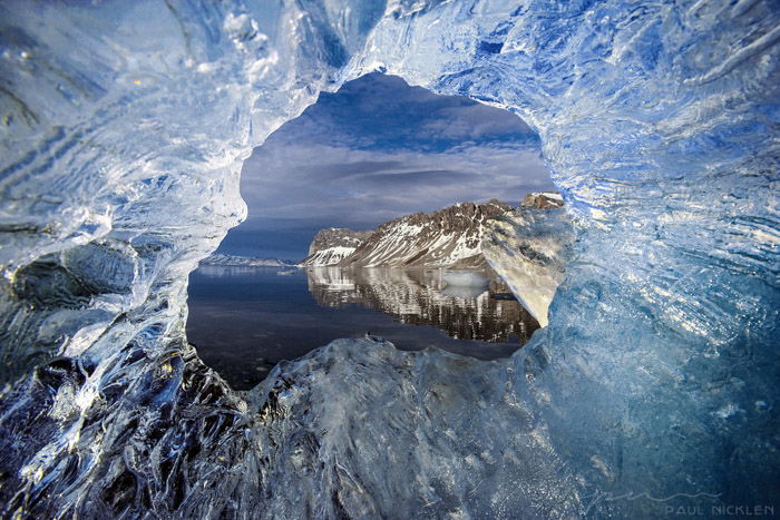 A seascape photographed through a hole in ice by Paul Nicklen. 