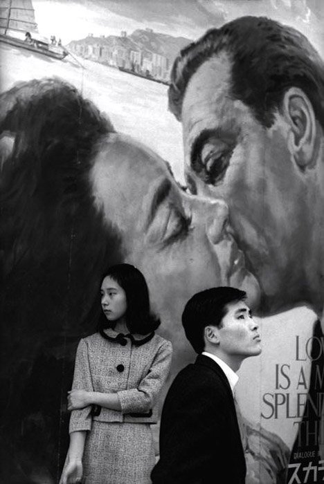 Henri Cartier-Bresson photo of a man and woman standing juxtaposed against a painted background of a couple kissing.