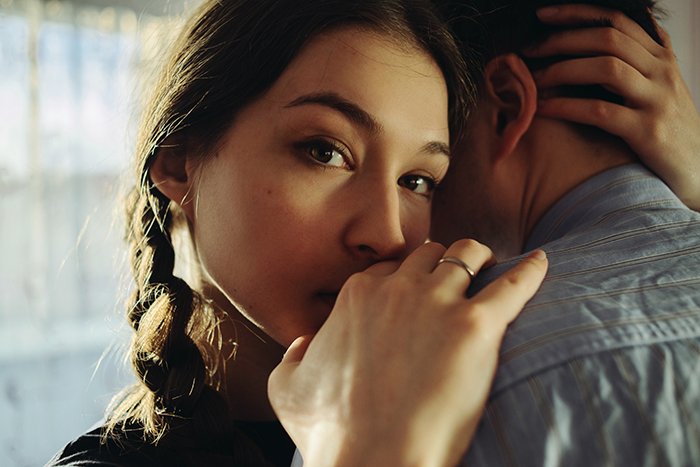 Close up portrait of a couple in an embrace, the girl looks towards the camera - using reflectors to enhance natural light portrait photography
