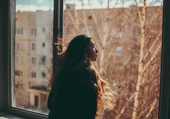 natural light portrait of a girl looking out of a large window