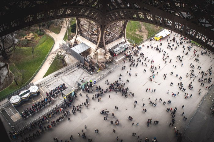 Travel photograph from the first floor of the Eiffel tower, looking down on many tourists below.
