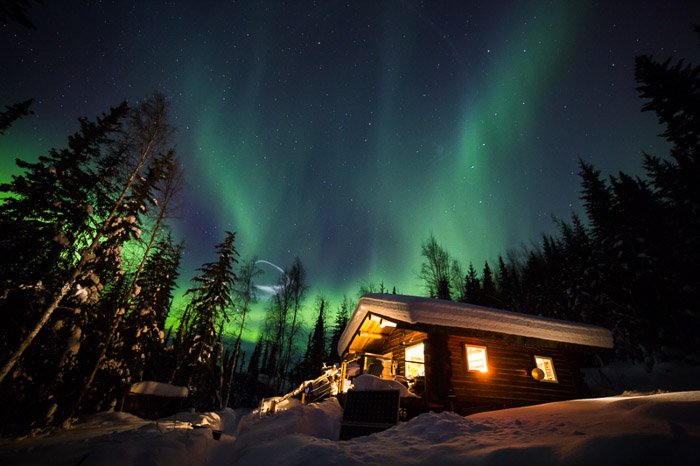 Beautiful view of the northern lights over a wooden cabin in the forest north of Fairbanks, Alaska