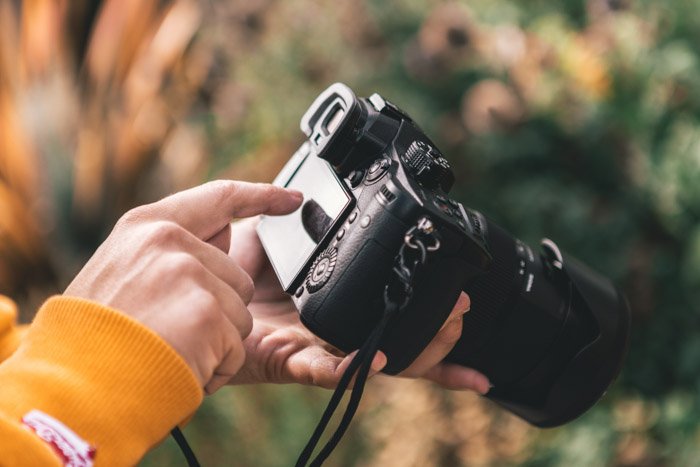 Close up of a persons hands holding a panasonic gh5 outdoors