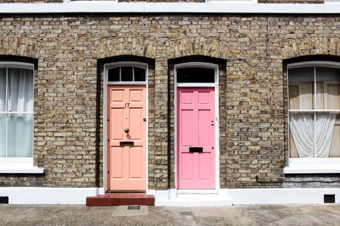 Street photography of 2 pink front doors of brick houses.