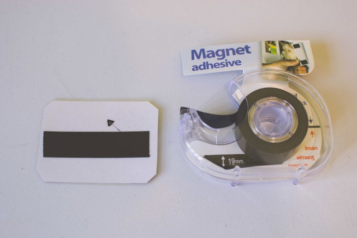 A magnet with a piece of adhesive magnet tape attached to the back of a photo as an idea for what to do with photos