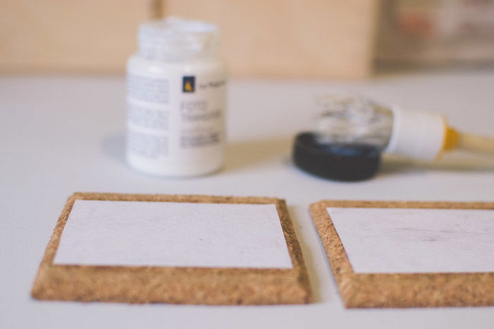 A close-up photo of gluing photographs to coasters as an idea of what to do with photos