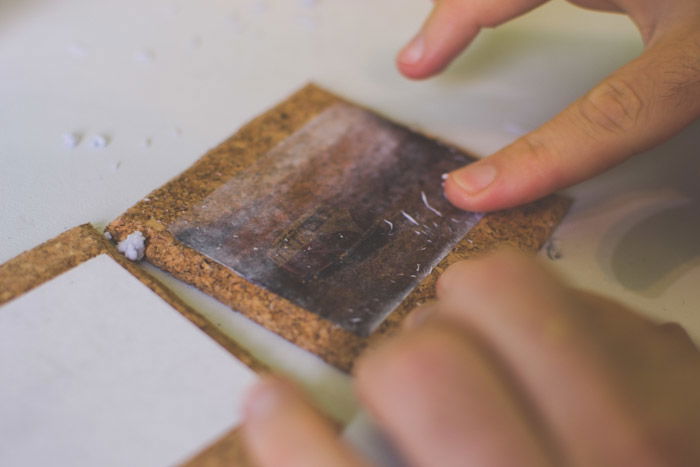 A close-up photo of sticking photographs to coasters as an idea of what to do with photos