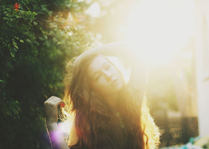 Dreamy light filled portrait of a dark haired girl with a blurry forest background.