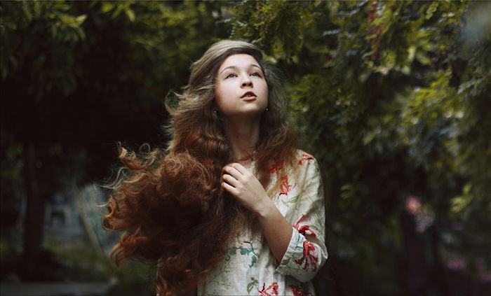 Portrait of a dark haired girl with a blurry forest background. 