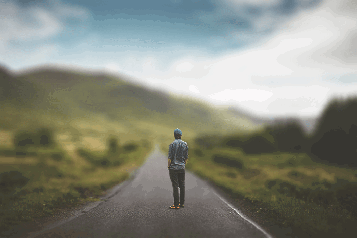 a man standing in the middle of a road with blurred background of a landscape