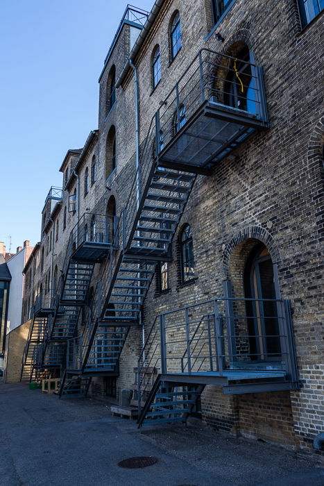 City photographed: A small alley with side view of a brick building in Copenhagen.