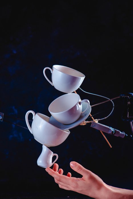 Una idea creativa de fotografía de salpicaduras de café de equilibrar las tazas de café que caen sobre un fondo azul oscuro