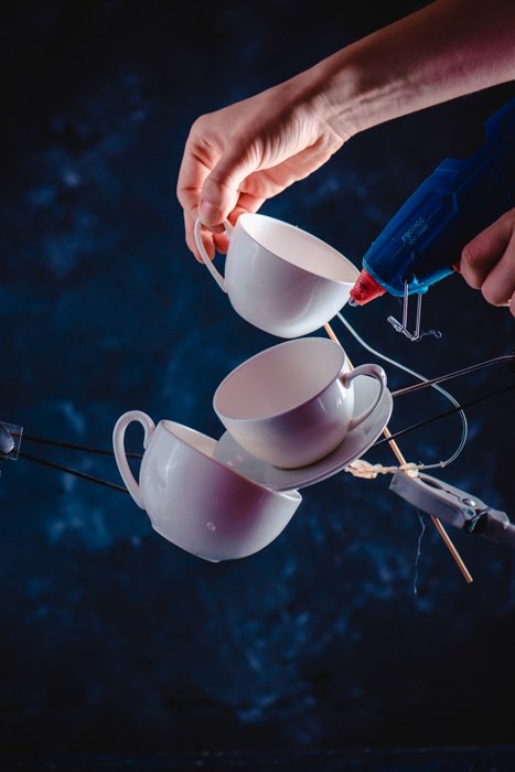 Una idea creativa de fotografía de salpicaduras de café de equilibrar las tazas de café que caen sobre un fondo azul oscuro