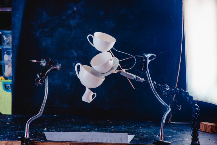 A creative coffee splash photography idea of balancing falling coffee cups on dark blue background