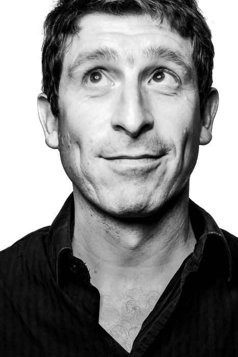 Black and white portrait of a man looking to the upper corner of the frame, making a funny face