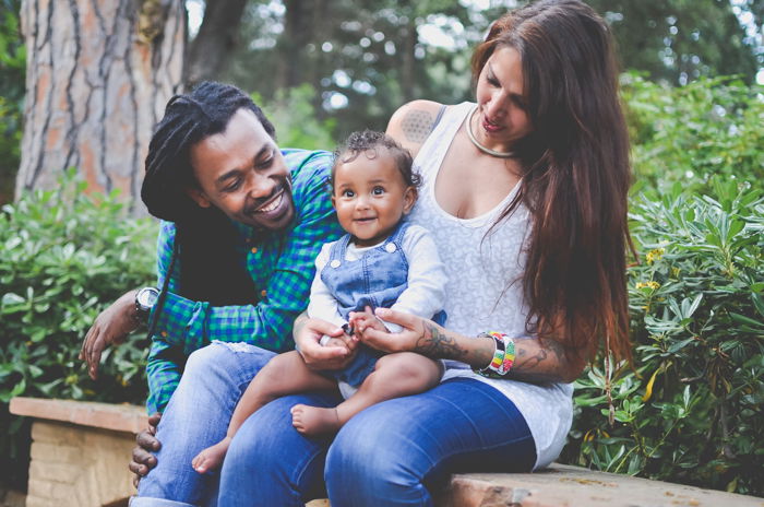 Family portrait photo of a couple and son sitting on a bench outdoors