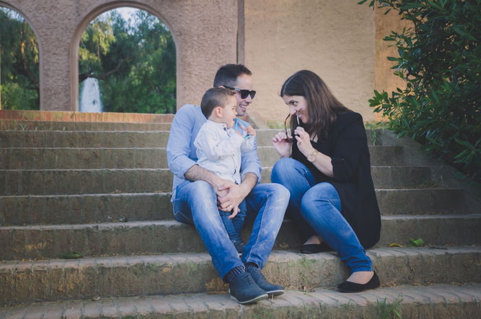 Family portrait photo of a couple and son sitting on outdoor steps 