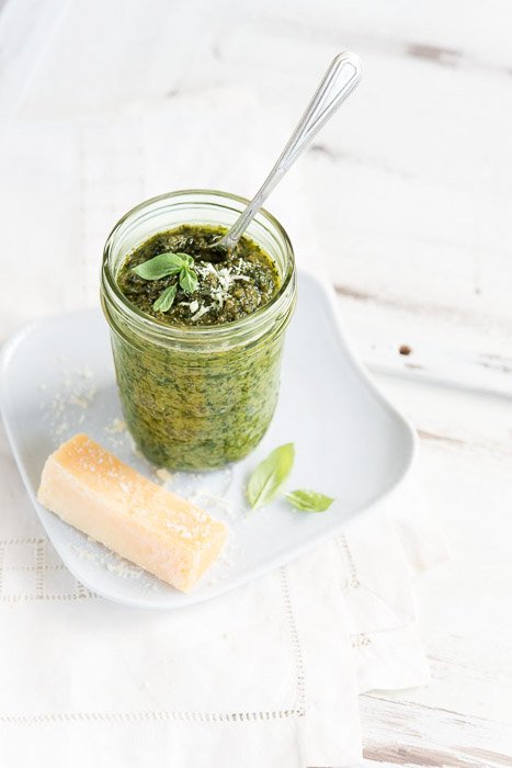 Bright and airy still life photography of a jar of green pesto shot with a macro lens.