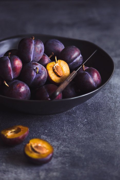 Still life photography of a bowl of plums ion dark background shot with a 105mm on a full frame. 10 Tips for Shooting with Macro Lenses in Still Life Photography.