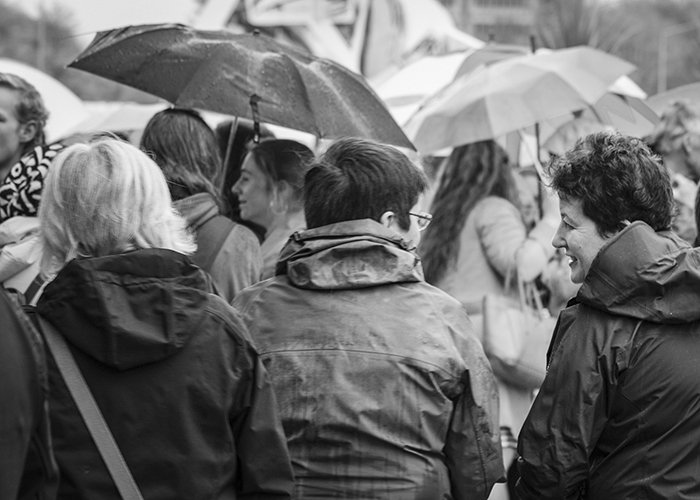 Black and white street photography of a group of adults in the rain. Rain photography