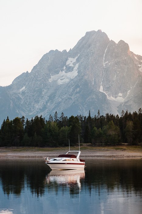 A serene image of a boat on a lake with mountain behind 