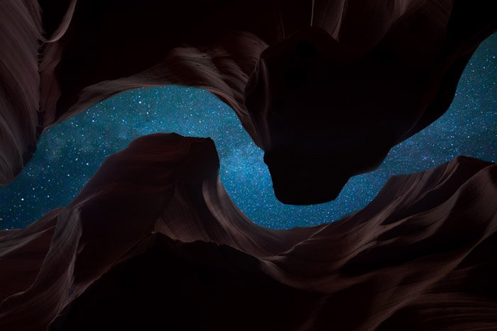 Stunning astrophotography shot of a star filled sky framed by cliffs