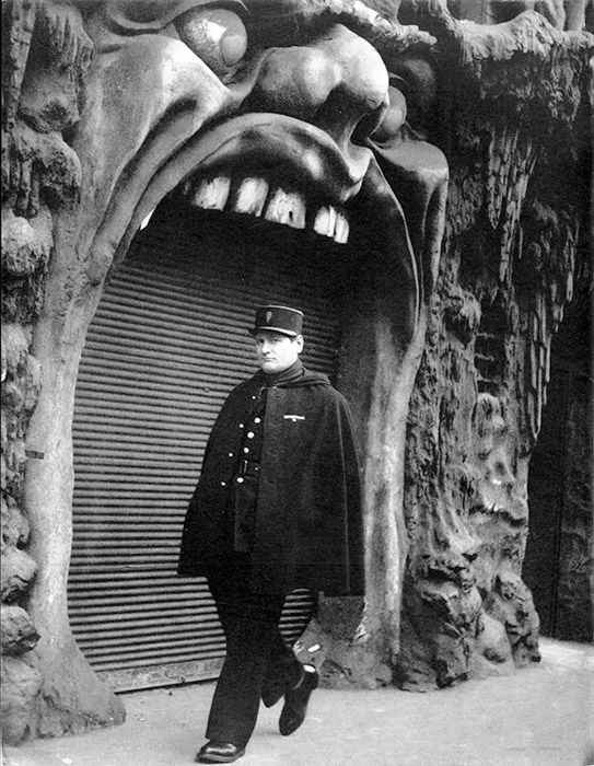 Black and white photo of a man walking by L'Enfer bar in Paris 