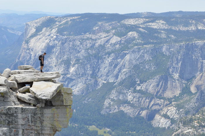 A man standing on the edge of a cliff with an impressive mountain landscape behind him demonstrating size weight balance in photography