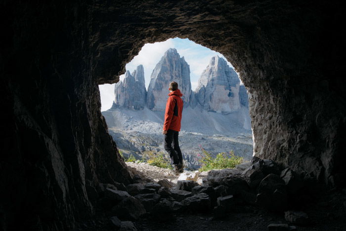 A hiker natural framed by a cave in the foreground 