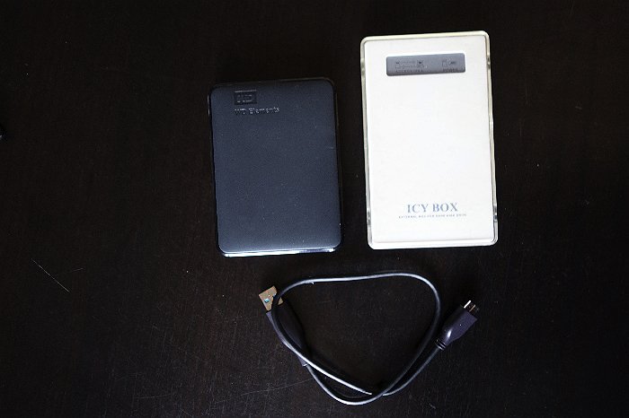 Overhead shot of WD passport external drive and a homemade HD for travel photography on black table