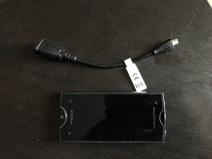 Overhead shot of a Sony Xperia Ray and microUSB OTG cable on black table
