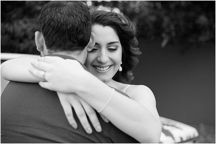 A black and white engagement photography shot of the couple embracing outdoors