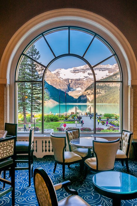 A stunning mountainous landscape shot through a large glass window with restaurant interior in the foreground - window how to make money with travel photography