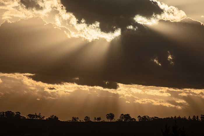 Dramatic clouds over the silhouette of a tree covered landscape