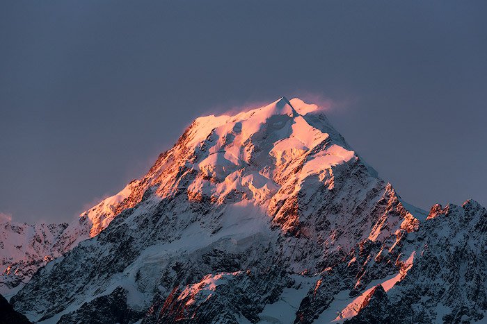 Icy mountain peak photo shoot with pink light reflected on the snow
