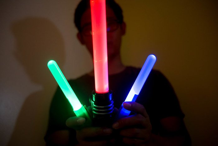 A man holding three colored light sticks for light painting photography