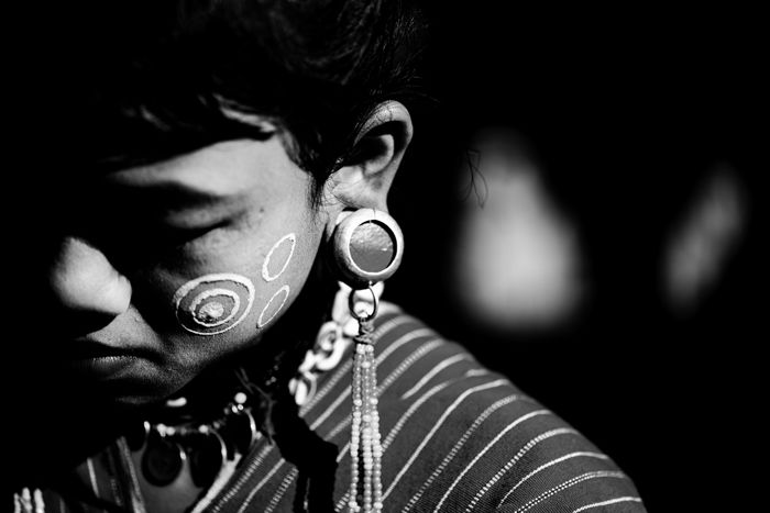 A low key monochrome photography portrait of a person wearing tribal make up and jewelry