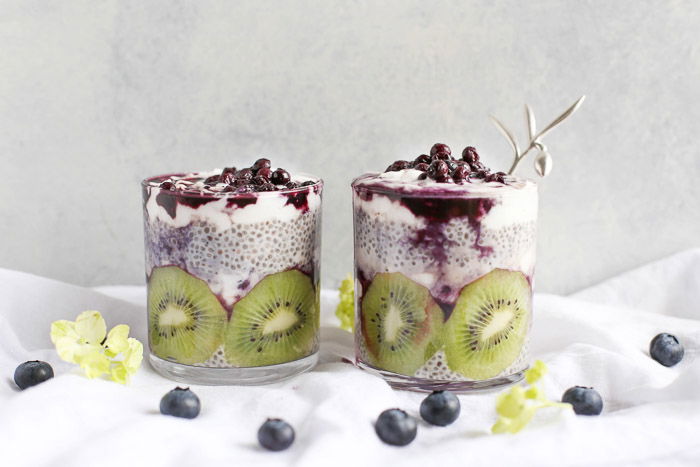 Bright and airy food photography of two dessert glasses filled with fruit and cream on a white tablecloth shot with a macro lens