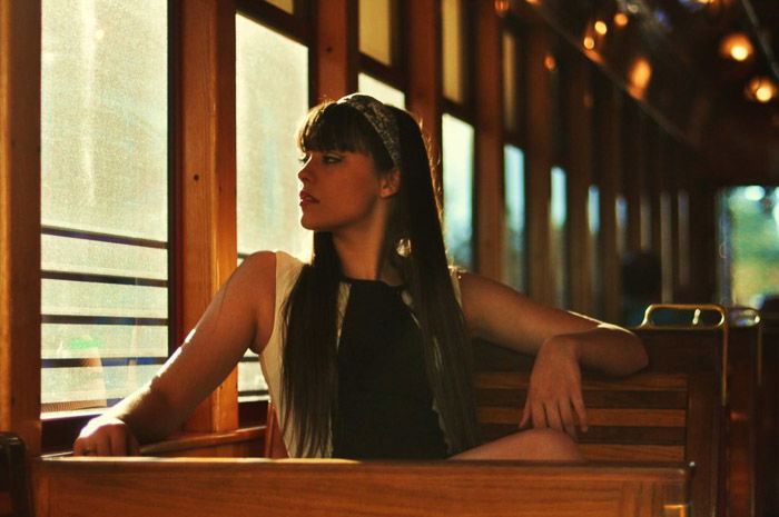 A female poses on a bench looking out the window for fashion model photography shoot.