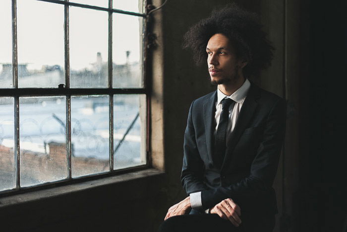 A natural light photography portrait of a man in front of a window in Bushwick, Brooklyn 