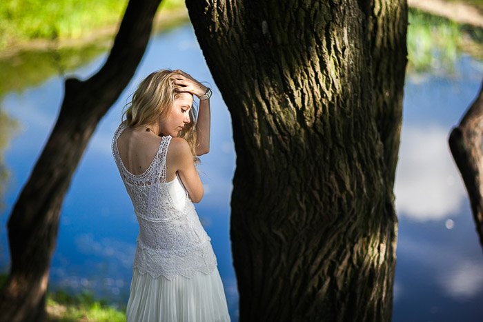 An outdoor portrait photography shot of a girl posing by a tree and water in park in Saint Petersburg