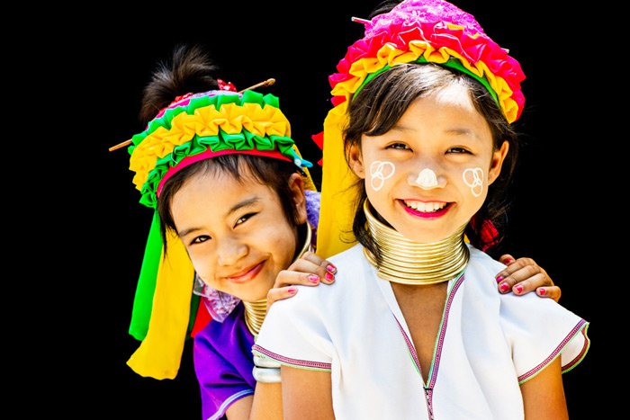 Photo of two Kayan girls enjoying having their portrait made in an outdoor portrait photography studio in their village in north Thailand.
