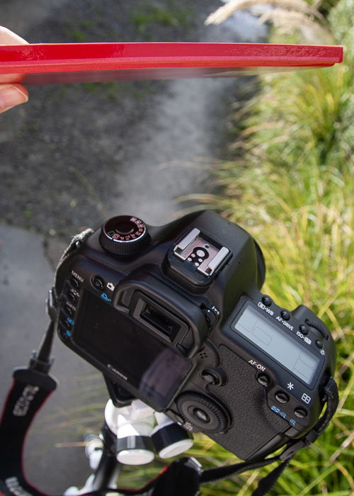 Photo of a tripod and camera with the photographer using a notebook as photography equipment.