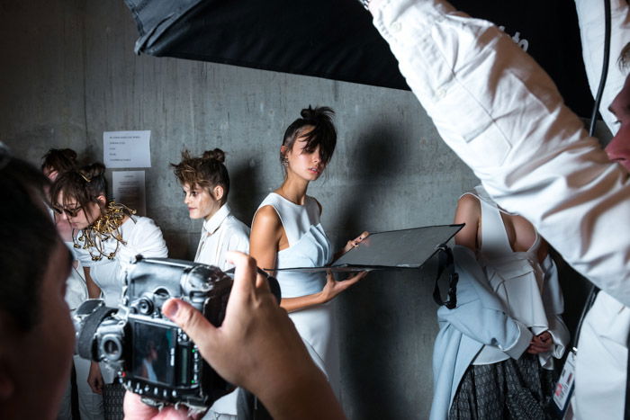 A group of models and photographers backstage at a fashion shoot