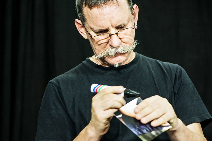 Close up of a man using a black marker to darken the edge of a print for a photomontage.