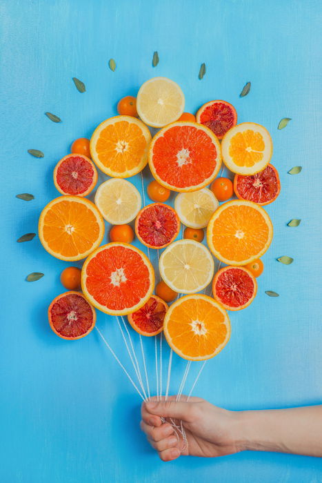 A still life photography ideas arrangement of oranges made to look like a bunch of balloon, on blue background