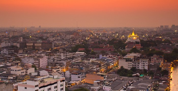 Cityscape view of Bangkok skyline with Golden Mount in the distance at sunset. 