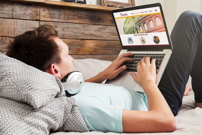 A photo of a man in bed using a laptop. 
