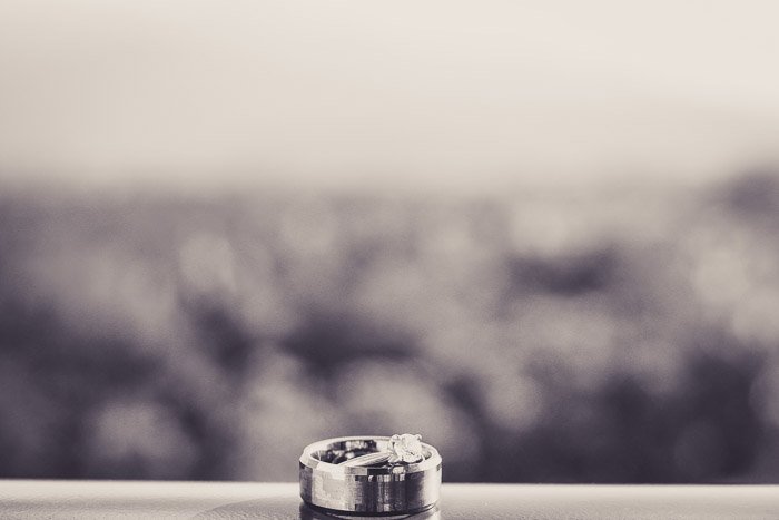 A black and white close up photo oof a wedding ring on a window sill. 