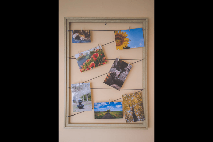 Multiple photos hanging form elastic string in a wood frame as an idea for what to do with photos